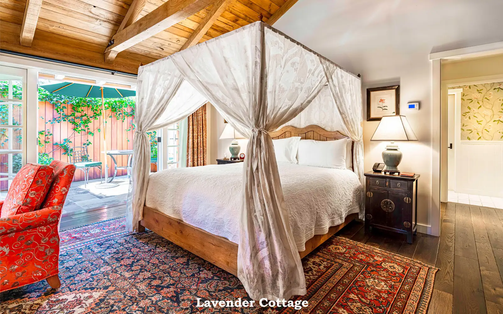 Lavender: the canopy bed on a Persian rug, a red armchair and French doors open to the patio.