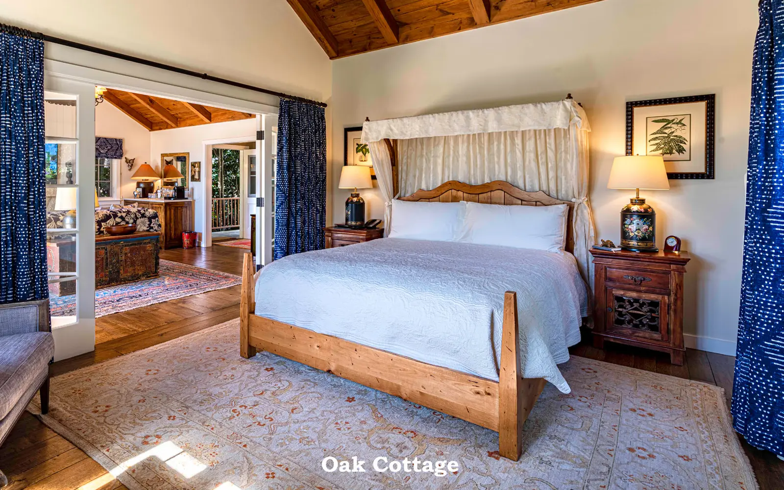 Oak: the bedroom with its wooden bed, blue curtains and the door open to the living room.