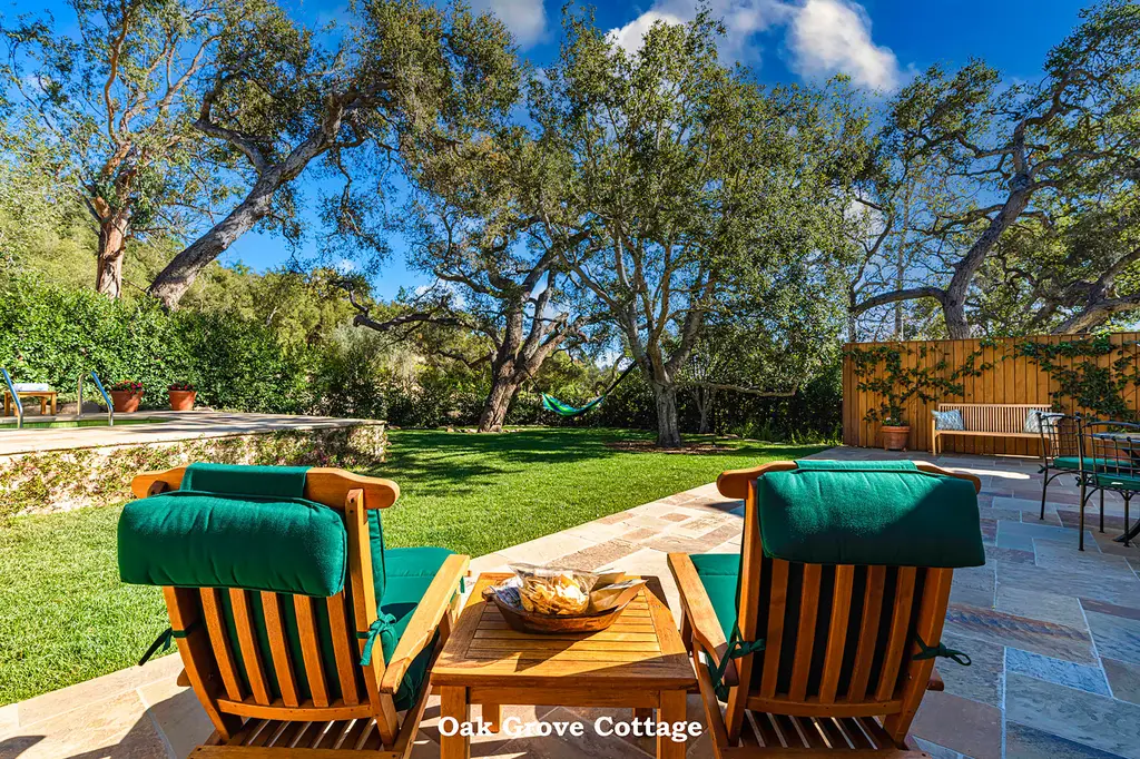 Oak Grove: 2 wooden loungers with green cushions on the patio, facing the lawn and the oaks.