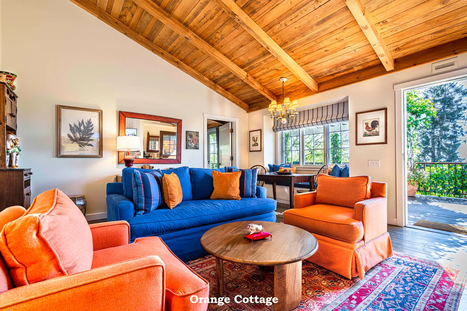 Orange: the living room with a blue sofa, orange armchairs, a round table and a timber ceiling.