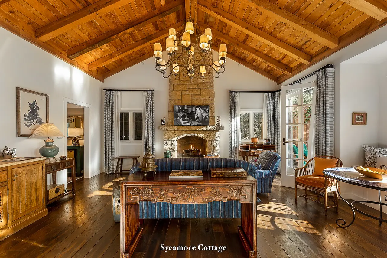 Sycamore: the living room with its stone fireplace, an iron chandelier and a trussed timber ceiling.