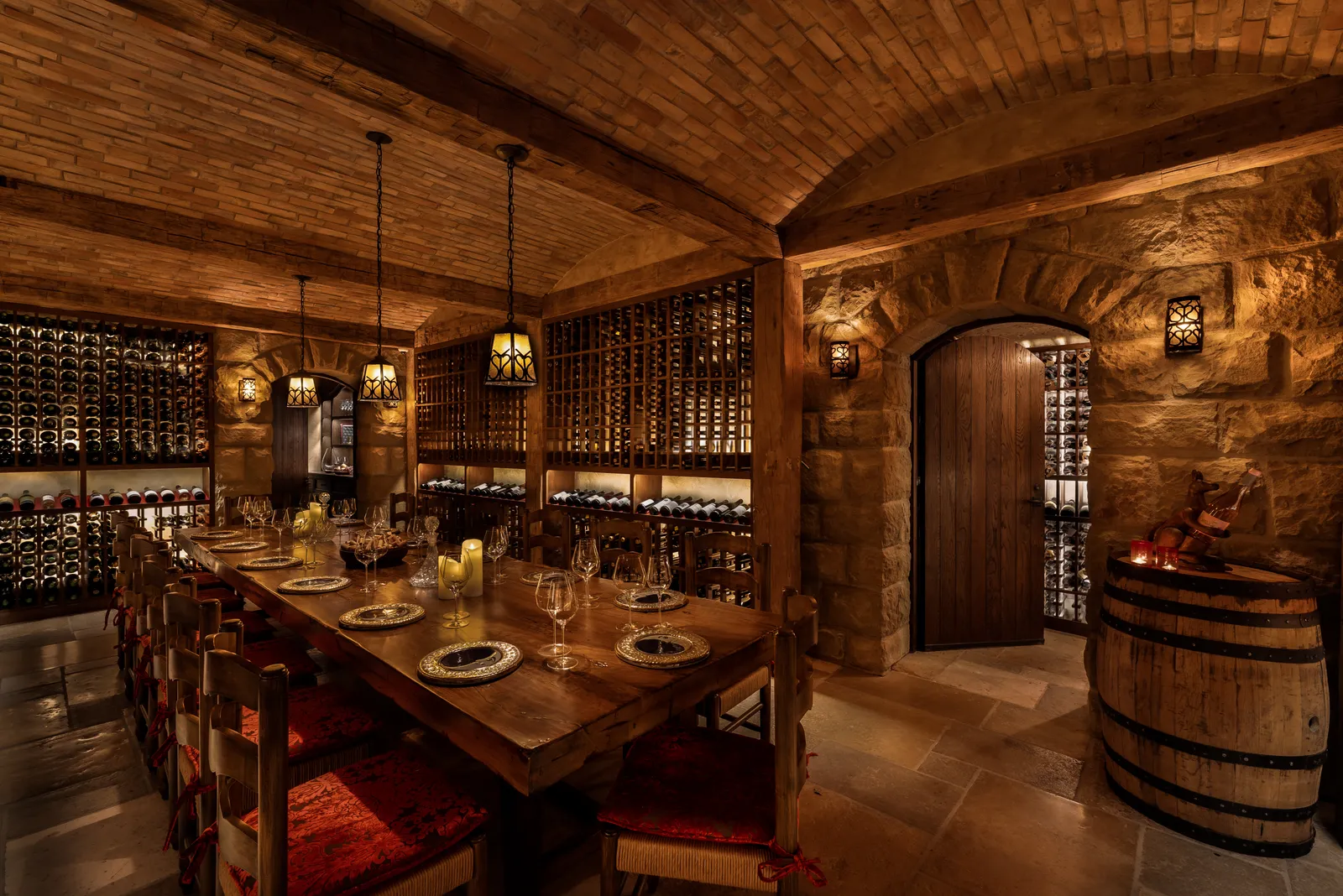 The Secret Cellar: a long table laid between walls of bottles, under a brick vault, with a barrel beside the arched door.