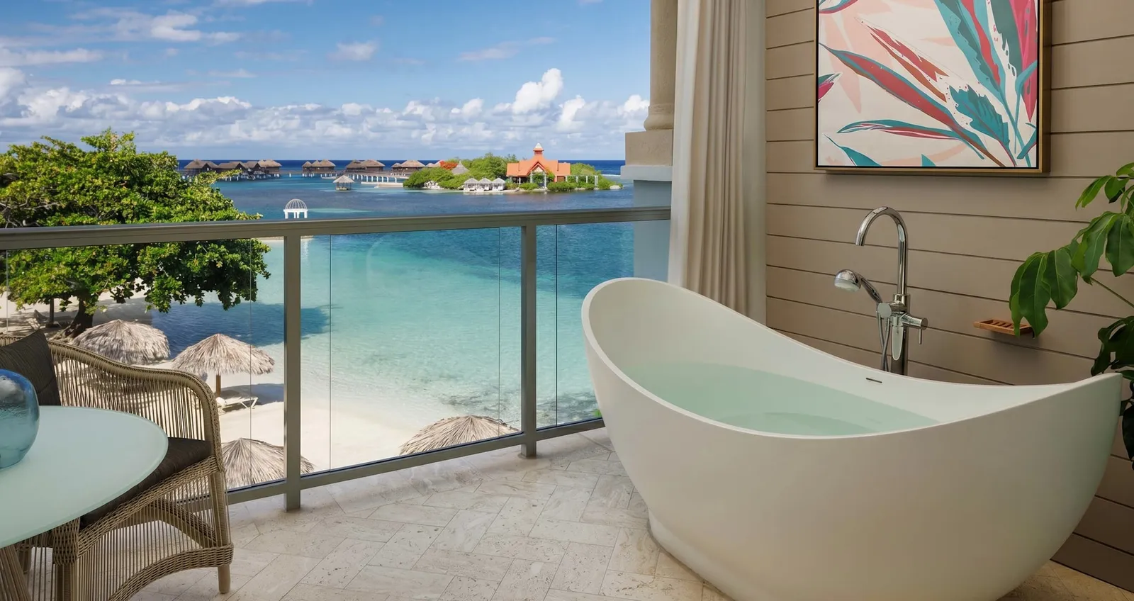 Official image: a balcony with a soaking tub and a glass rail, above the beach and facing the private island.