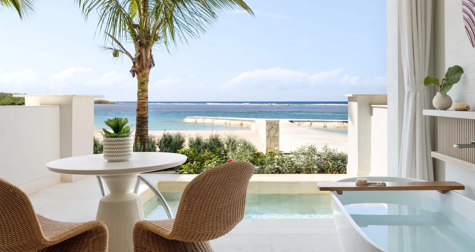 Official image: a terrace with a table, wicker chairs and a private pool behind a low wall, the beach beyond.