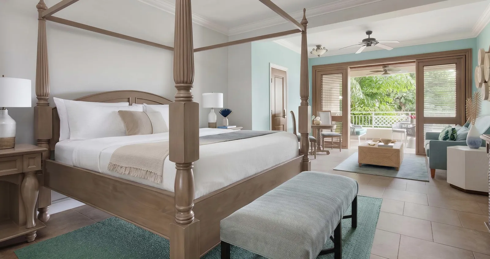 Official image: a four-poster bed and a sitting room open to the veranda, the garden beyond the doors.