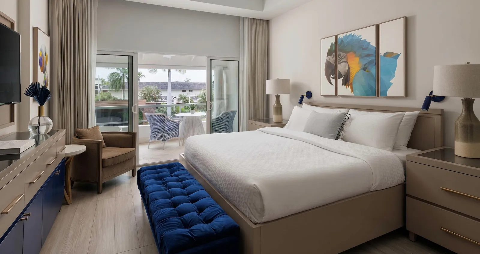 Official image: a bedroom with a blue bench at the foot of the bed, parrot prints and a balcony.