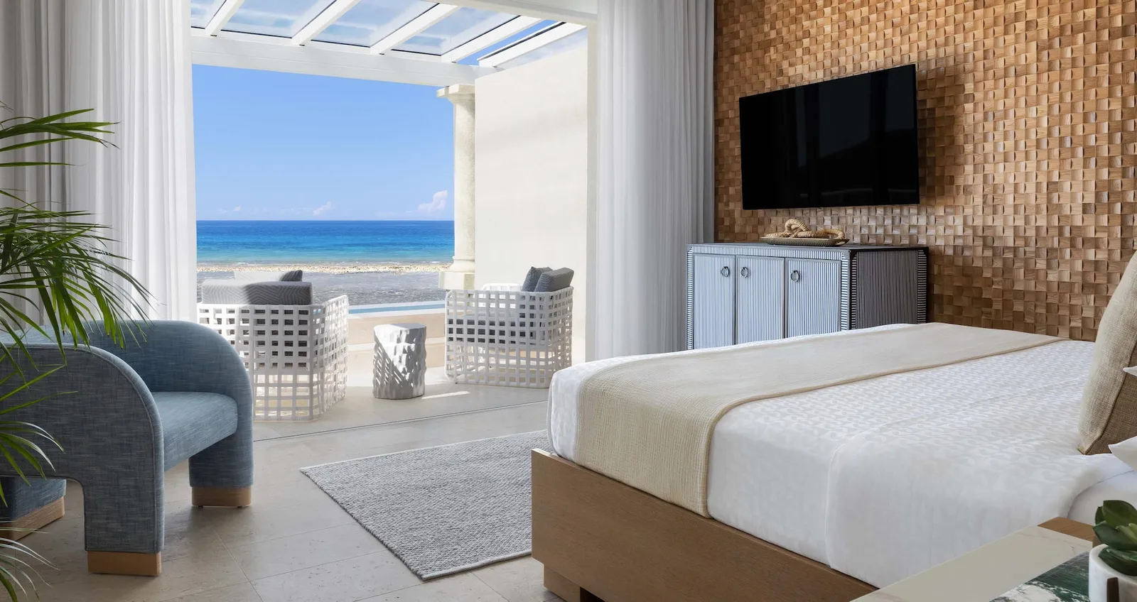 Official image: a bedroom under a glazed pergola, open to its terrace and the sea.