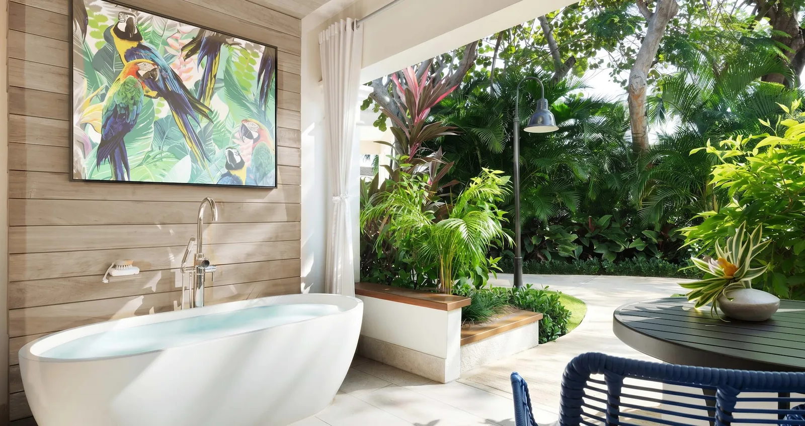 Official image: the soaking tub on the patio, against a timber wall, with tropical planting round it.
