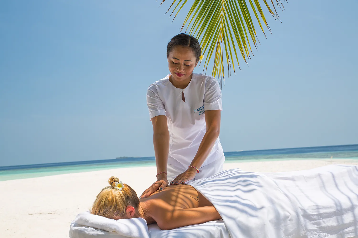 A massage on the beach: a Mvua Spa therapist and a guest on the table, with the sea behind.