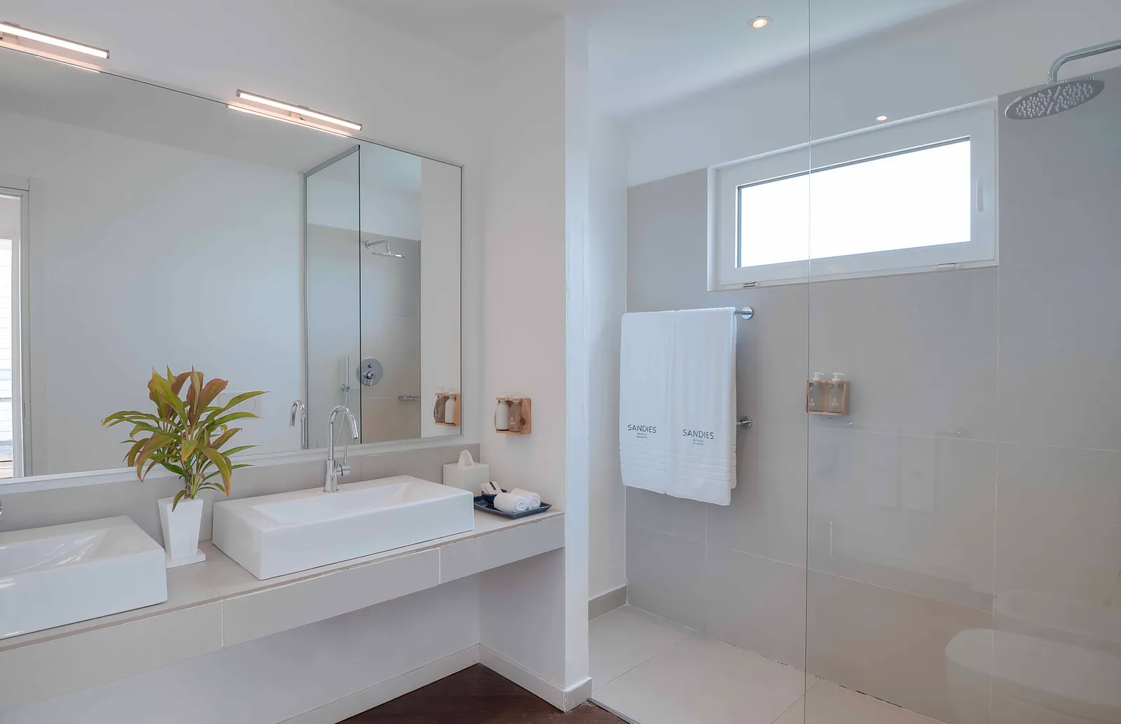 A water villa bathroom, with its double basin and the large walk-in shower behind glass.