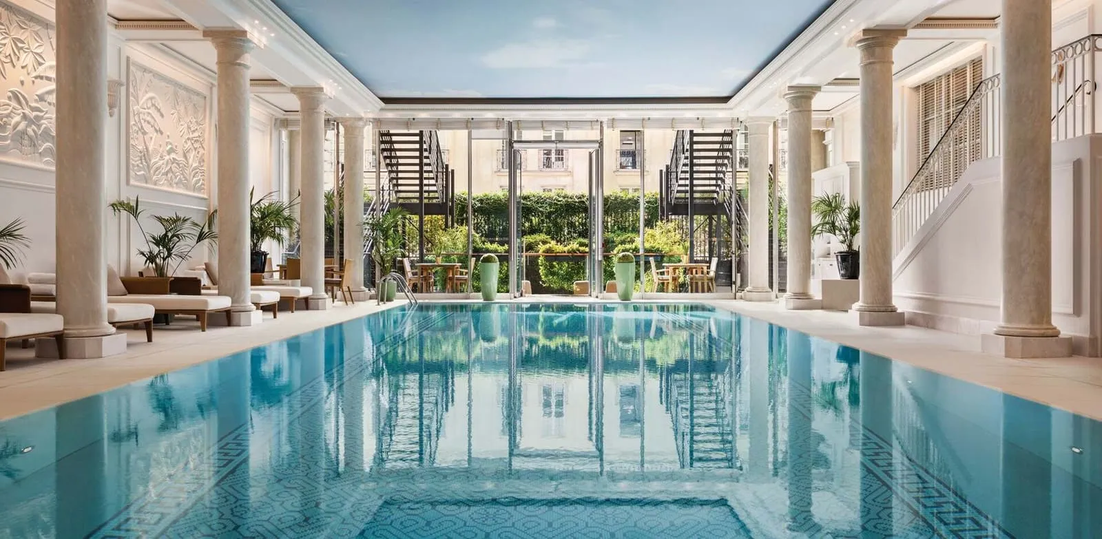 The indoor pool at Shangri-La Paris, with loungers and windows onto the garden