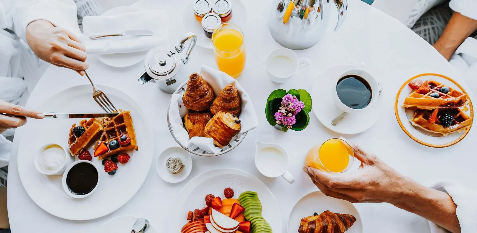 Breakfast at the table: waffles, croissants, fruit and juice