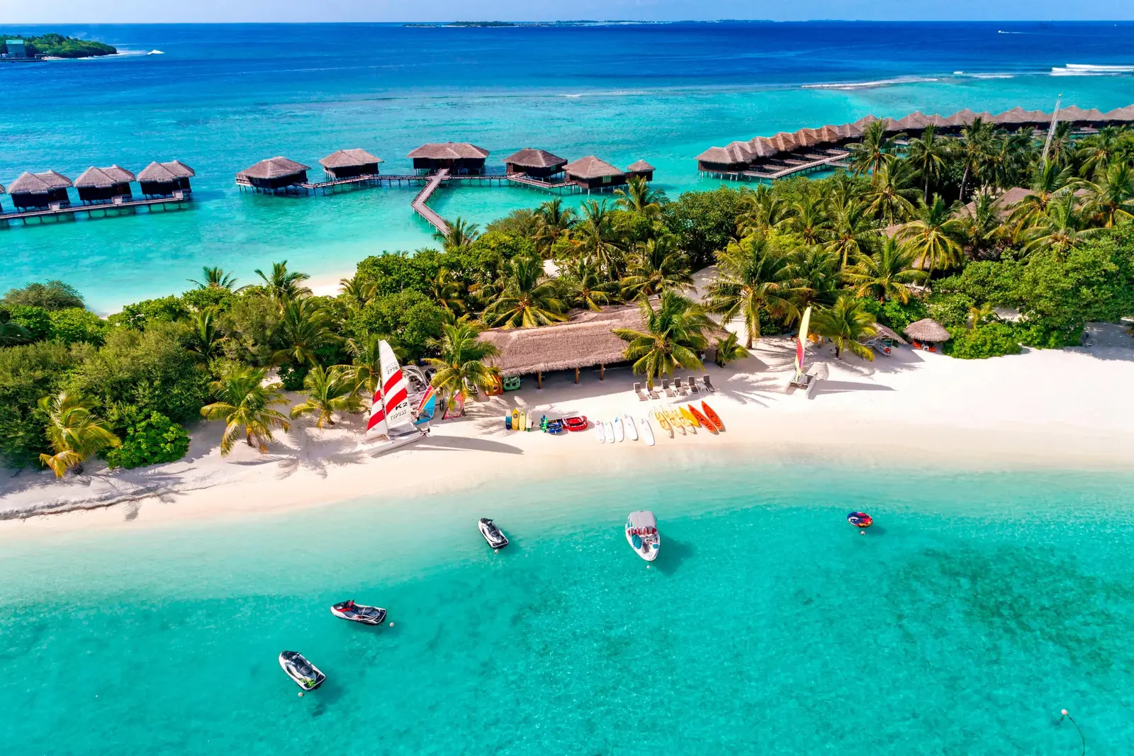 The white beach from the air, boats in the lagoon and the water villas behind