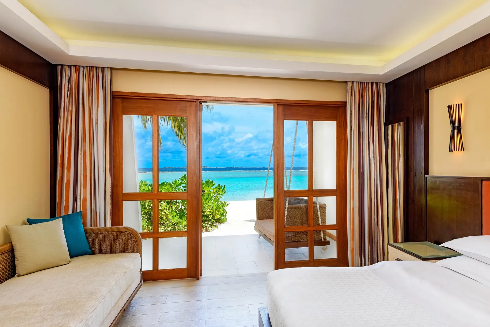 A beachfront Deluxe Guest Room, French doors open to the sea