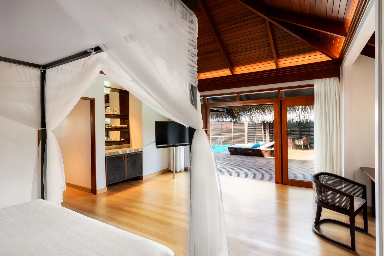 A Premium Overwater Villa bedroom, the canopy bed and the dark timber