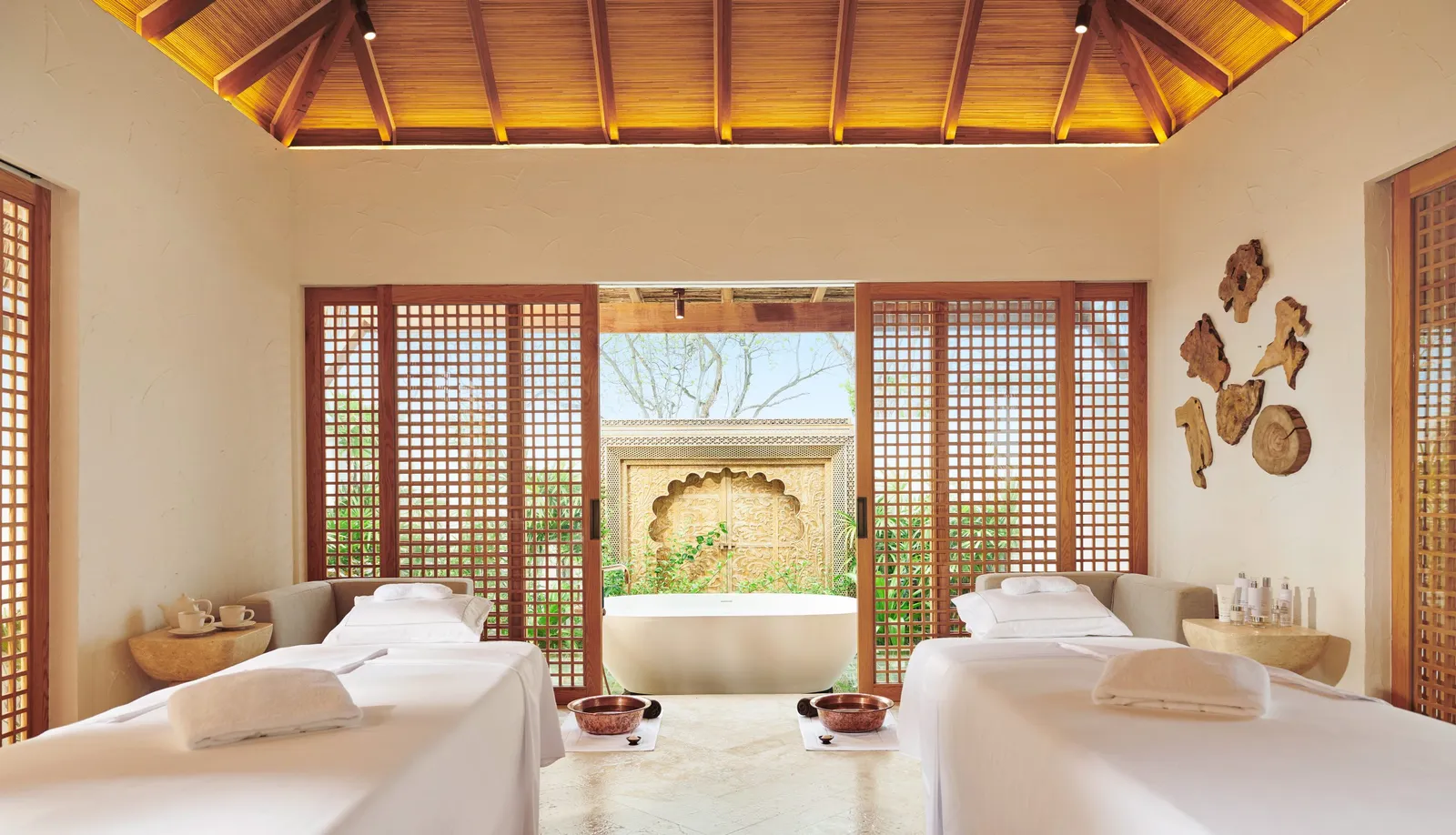 An Arufen Spa room with 2 treatment beds, its timber screens open to the garden and an outdoor bath.