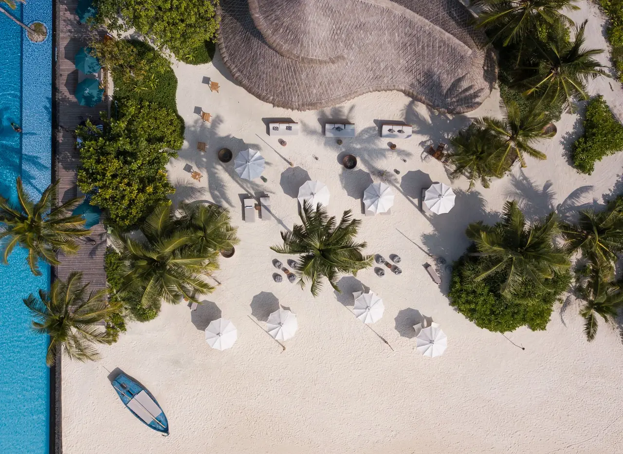 Onu Onu from above: white cushions and parasols on the sand beside the pool and a kayak.