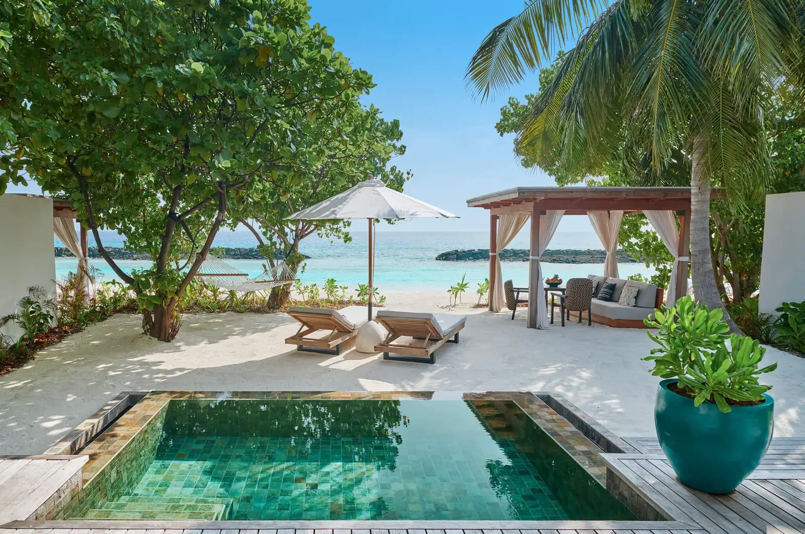 A Sunrise Beach Villa’s private pool, with loungers, a pavilion and the sea beyond the garden.