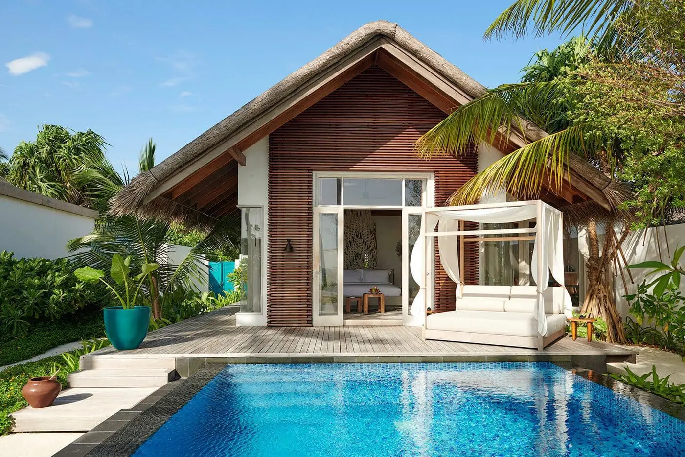 A Sunrise Deluxe Beach Villa with its pool in front, a canopied daybed and timber gable.