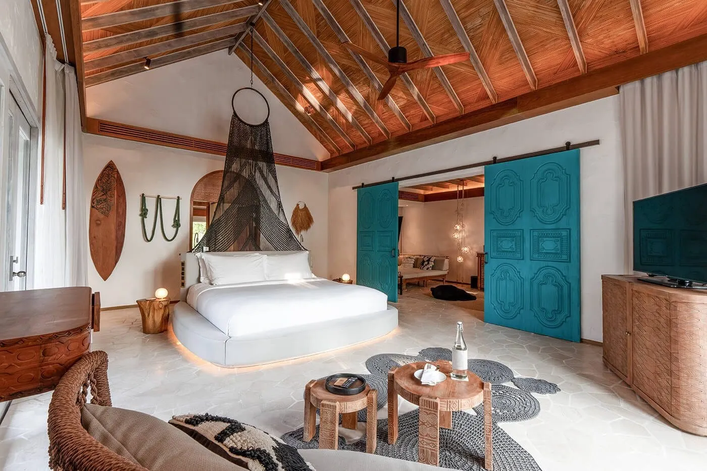 A Deluxe Beach Villa bedroom, with the bed, turquoise sliding doors and timber ceiling.