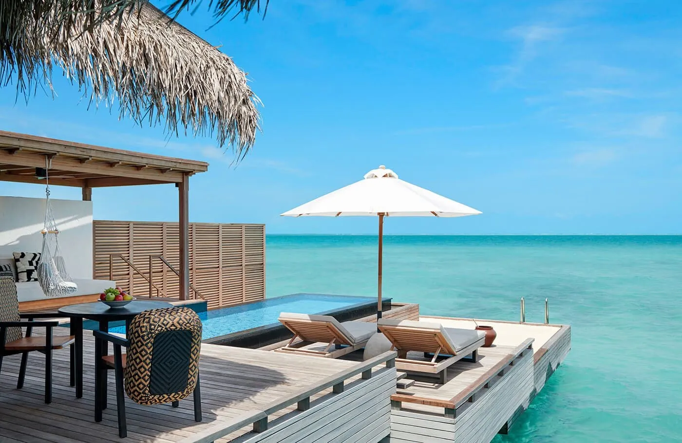 A Sunset Grand Water Villa’s deck, with its table, pool and turquoise lagoon.