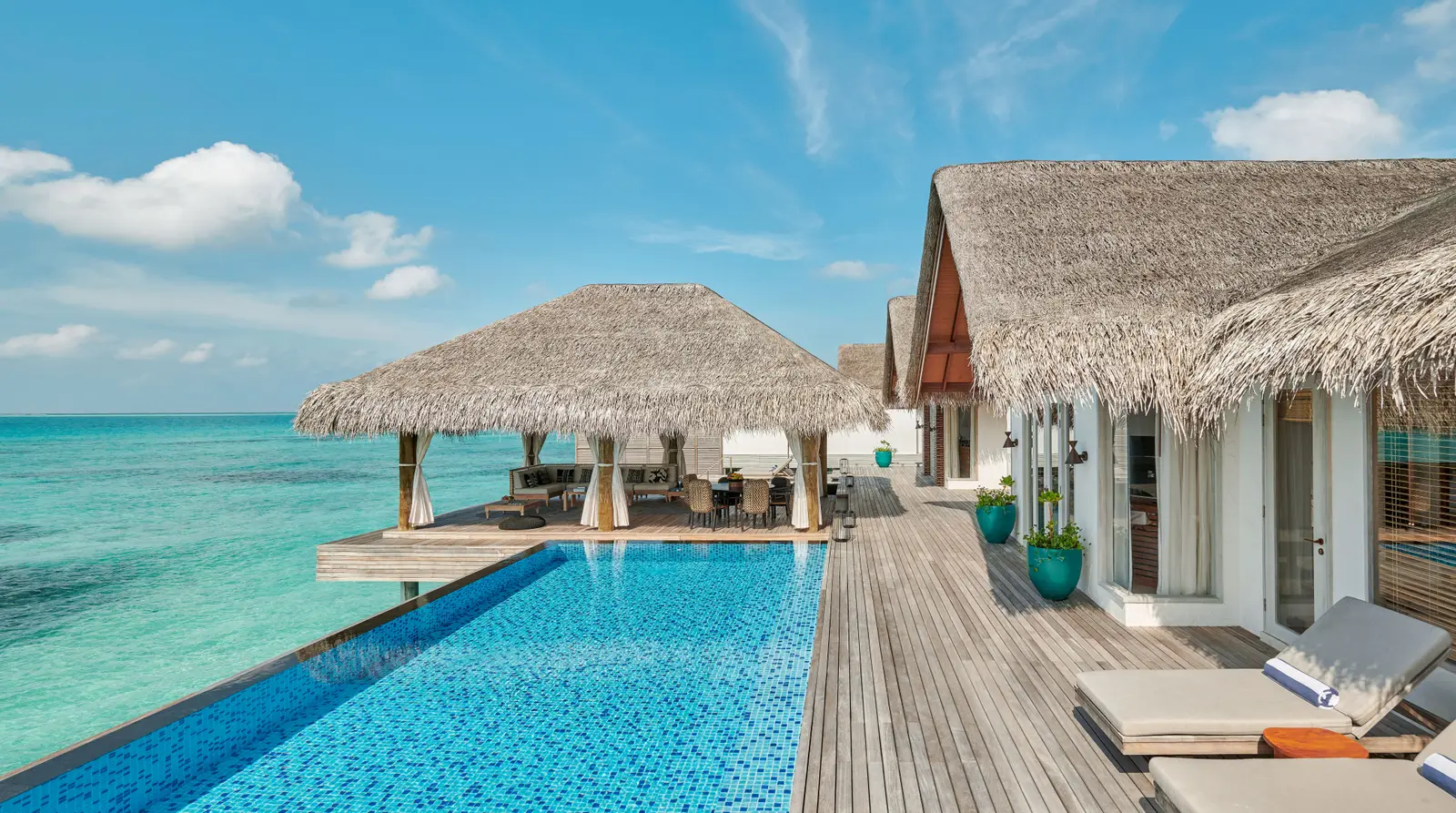 The long infinity pool of a multi-bedroom water villa, with the thatched pavilion at the end.