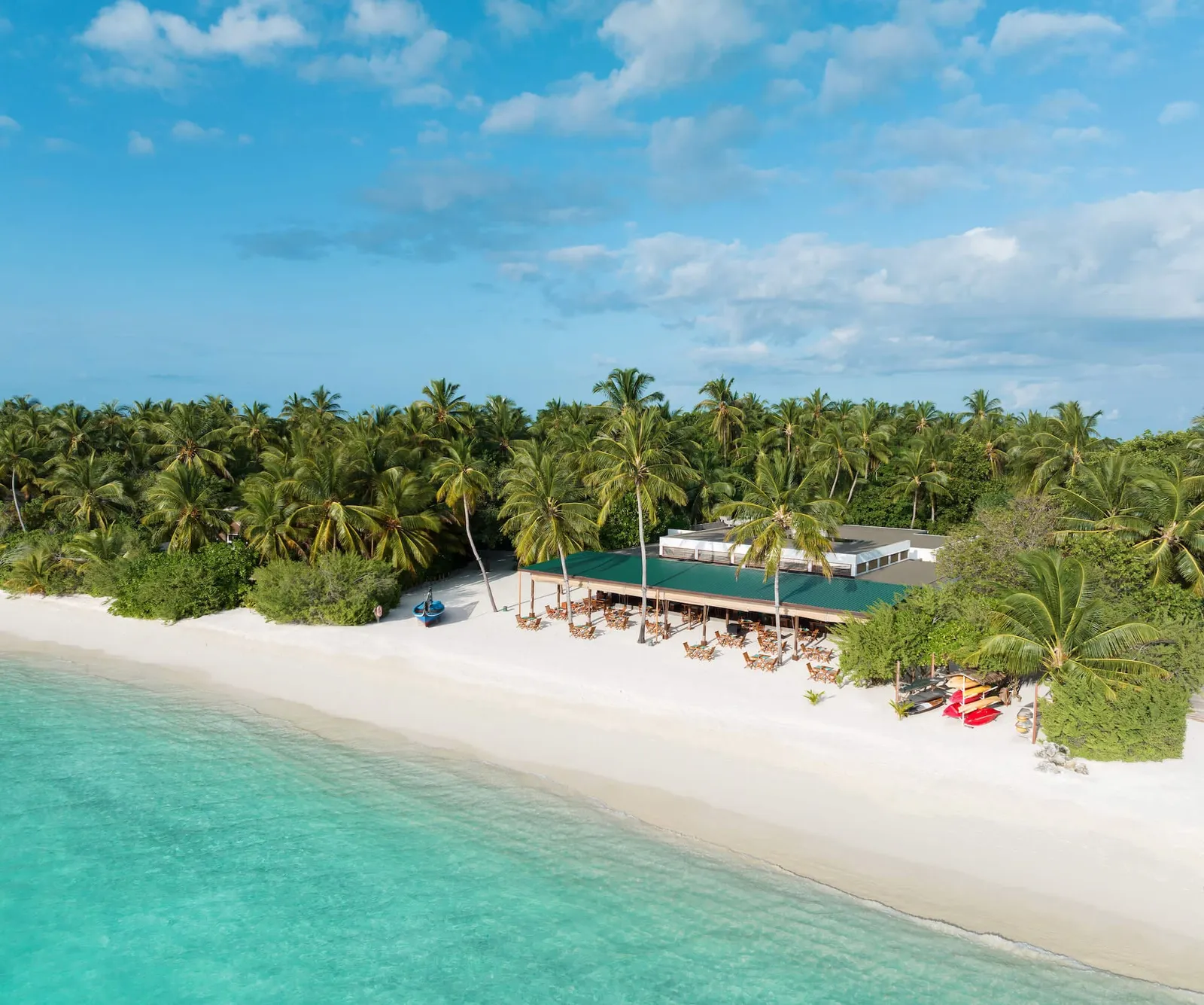 The white beach in front of Raha Market, with its parasols, palms and pale lagoon.