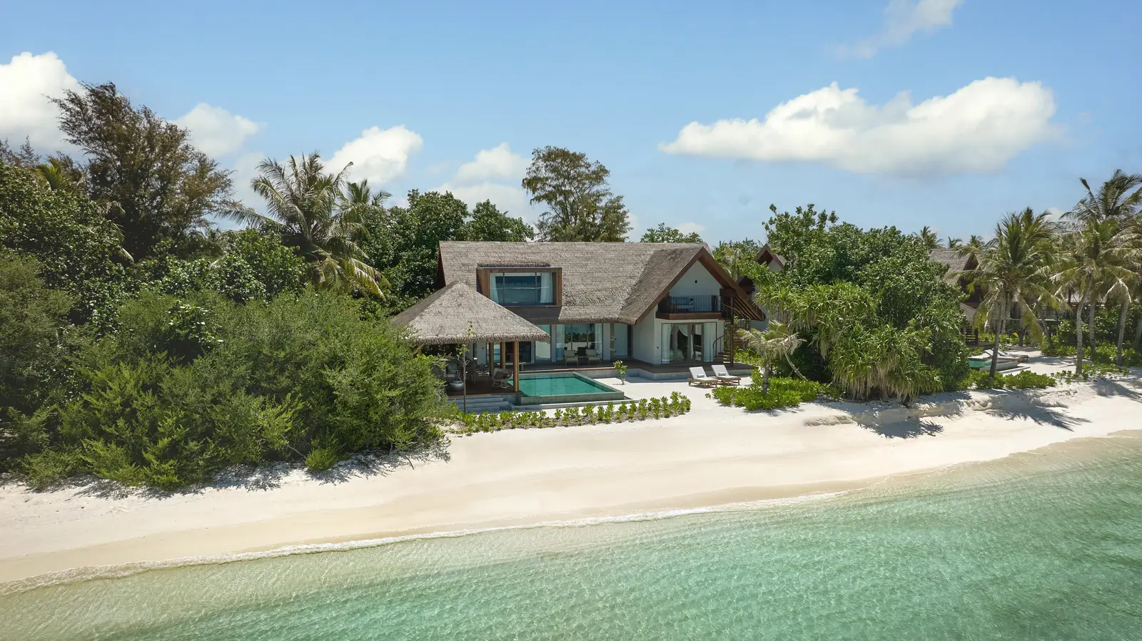A Beach Retreat on the beach, its pool in front, among the palms