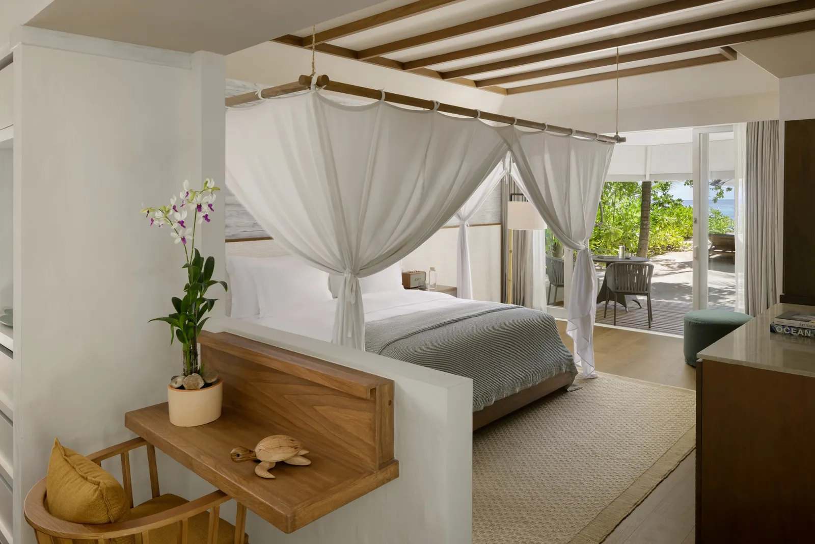 A Beach Villa bedroom: the four-poster bed with white nets and the door open onto the garden