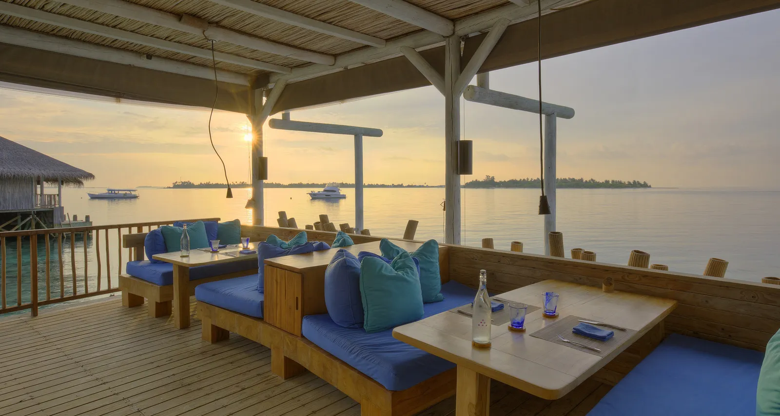 Chill Bar’s terrace over the water at sunset, blue cushions and timber tables
