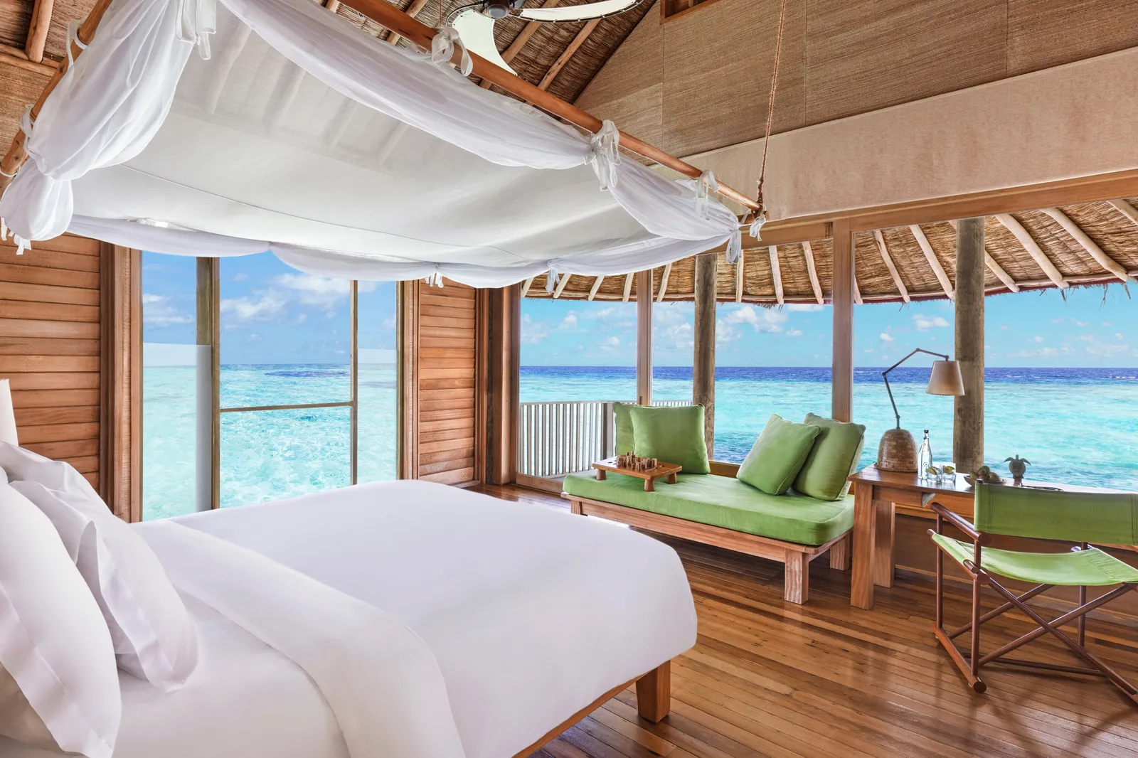 An Ocean Water Villa’s bedroom, the canopy bed and the sea beyond the door