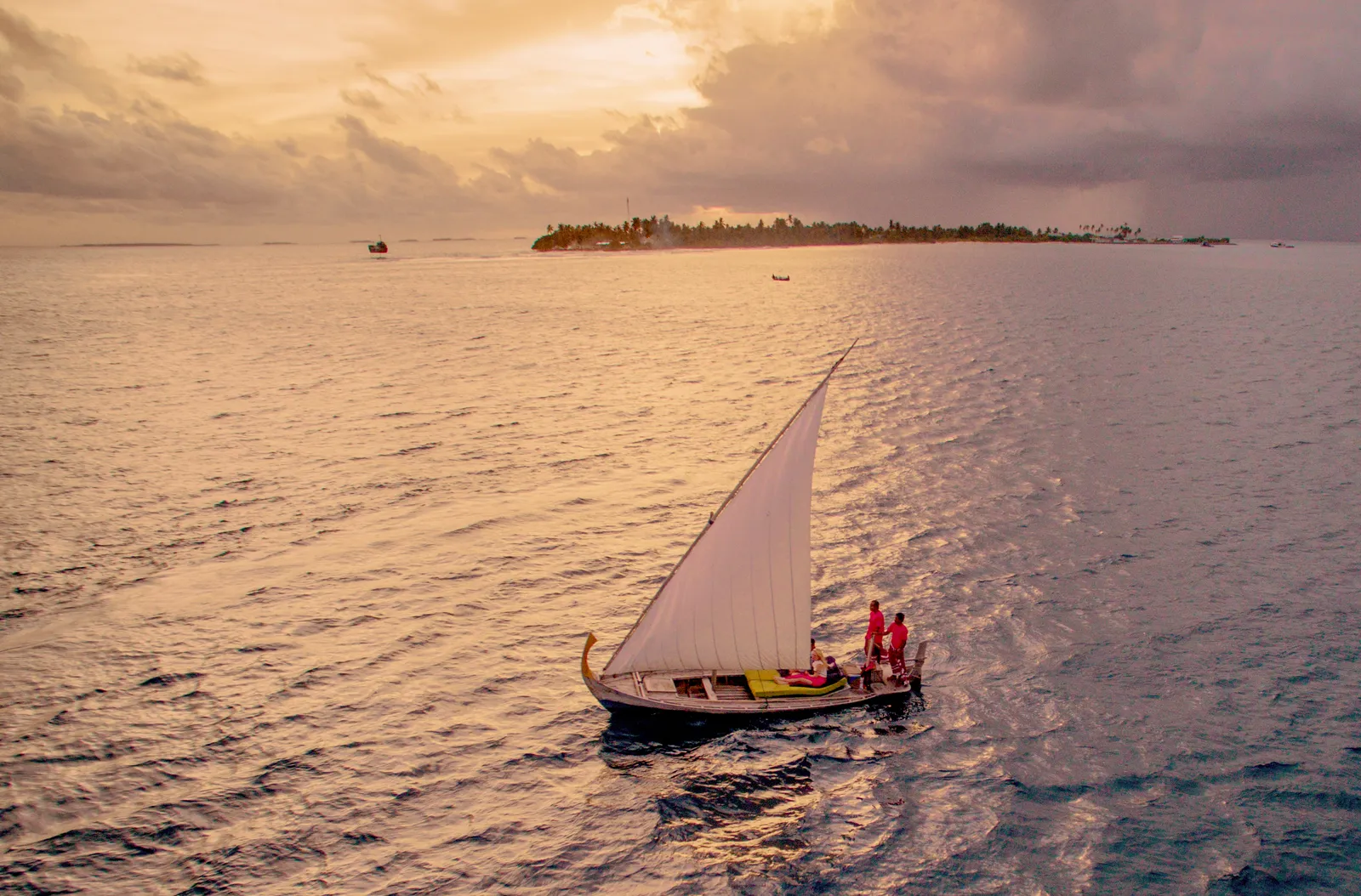 A sailing dhoni at sunset, the island in the background