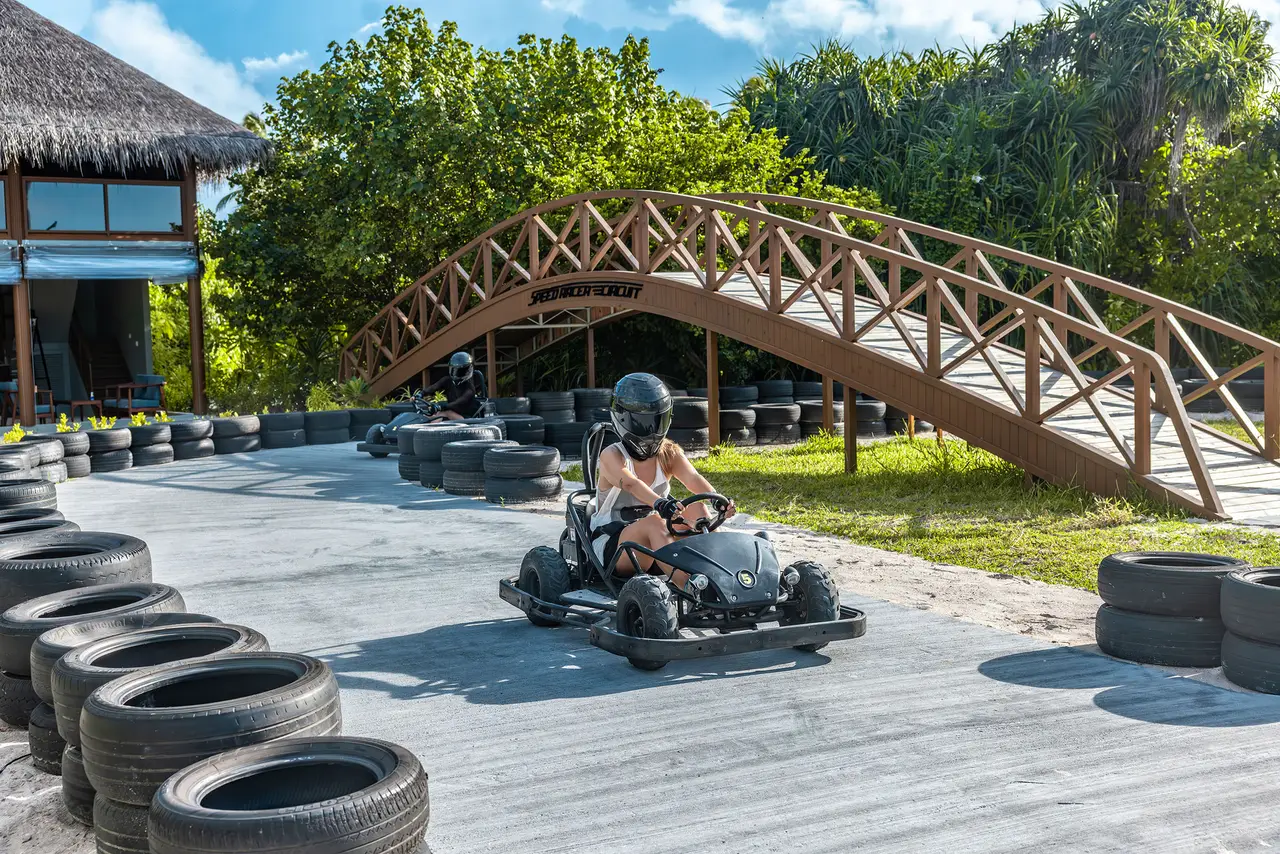 An electric go-kart on the track, between tyres and under a wooden bridge