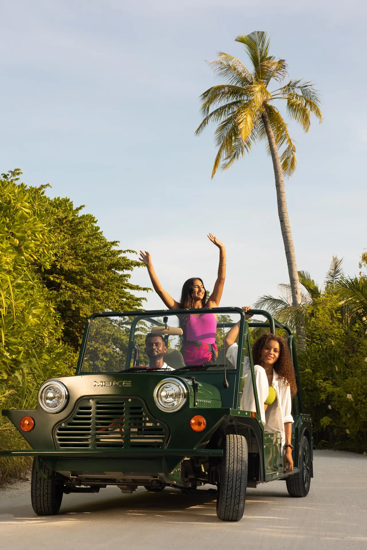2 young women in an electric Moke among the palms
