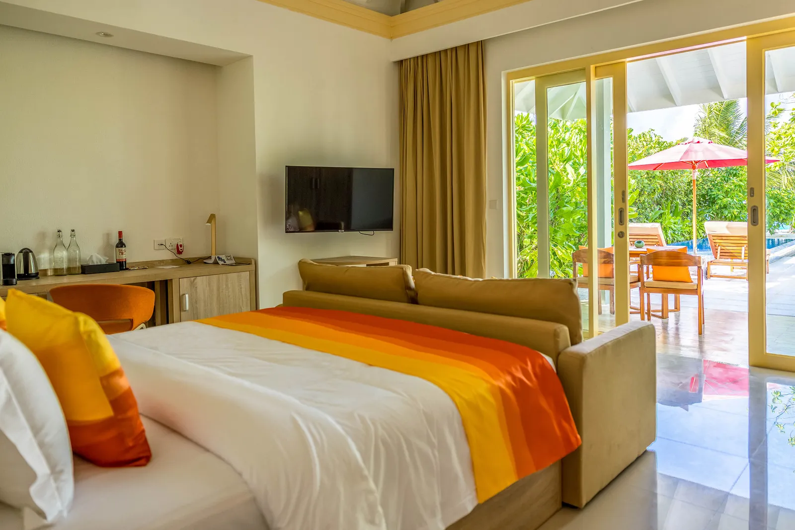 Inside a Pool Beach Villa, the bed and the door open onto the garden