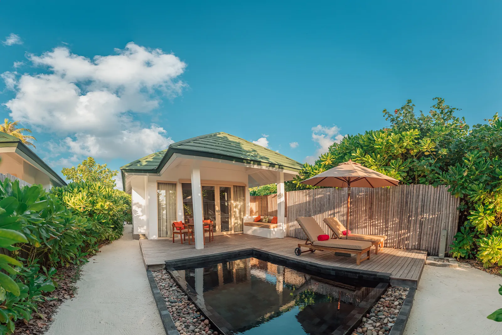 A Sunset Pool Beach Villa, its dark pool before the house among the palms