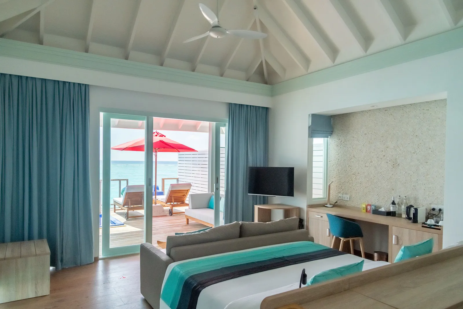 Inside a Water Villa, the bed and lounge before the glass doors