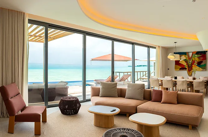 Curved living/dining space with peach sofa, deck and ocean beyond.