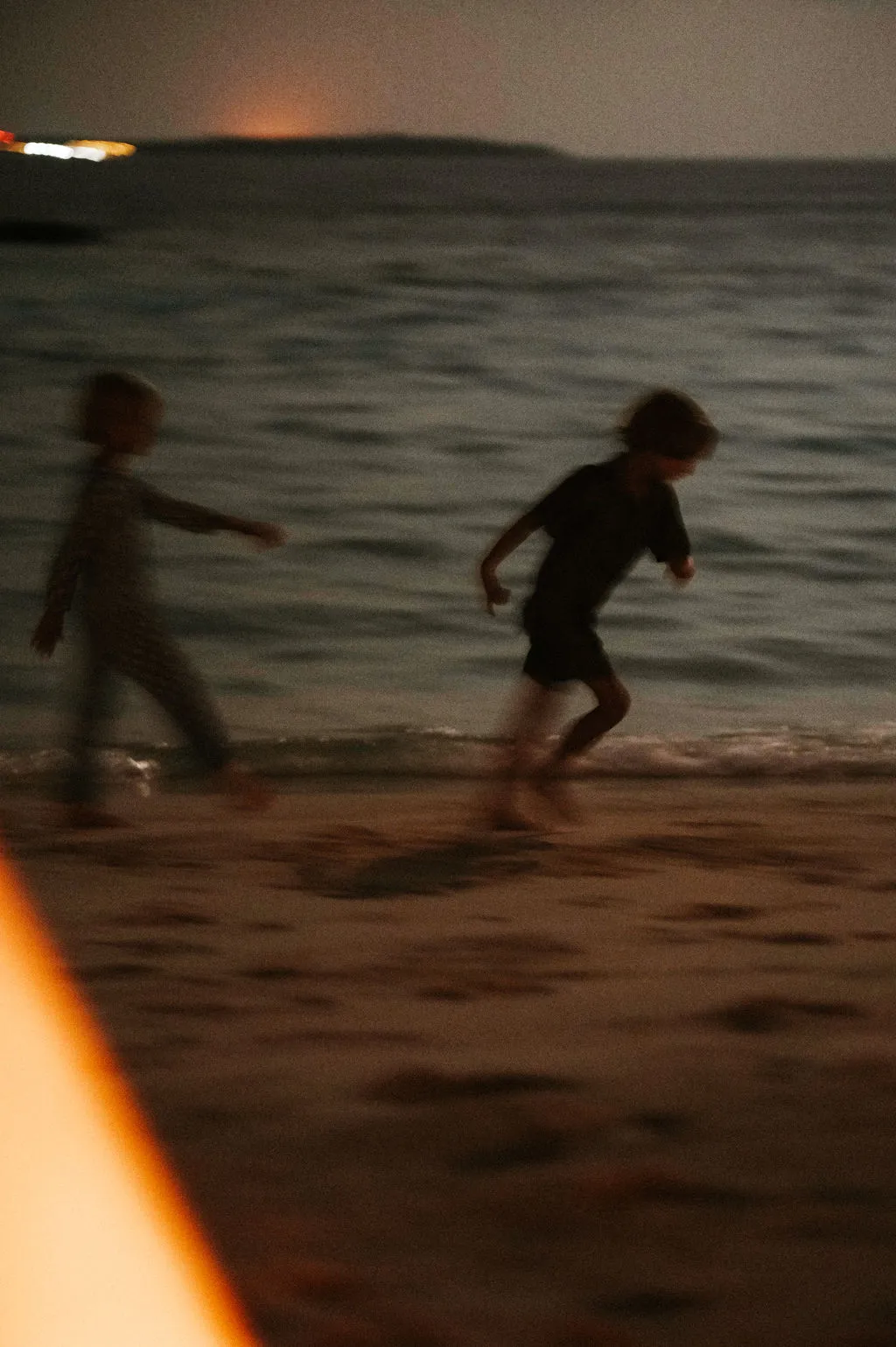2 children running along the beach at sunset