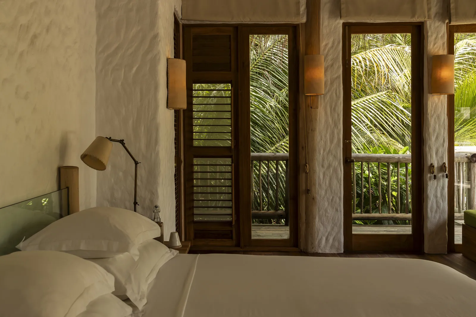 Crusoe with Pool: the bedroom, a white bed and shutters open to the palms