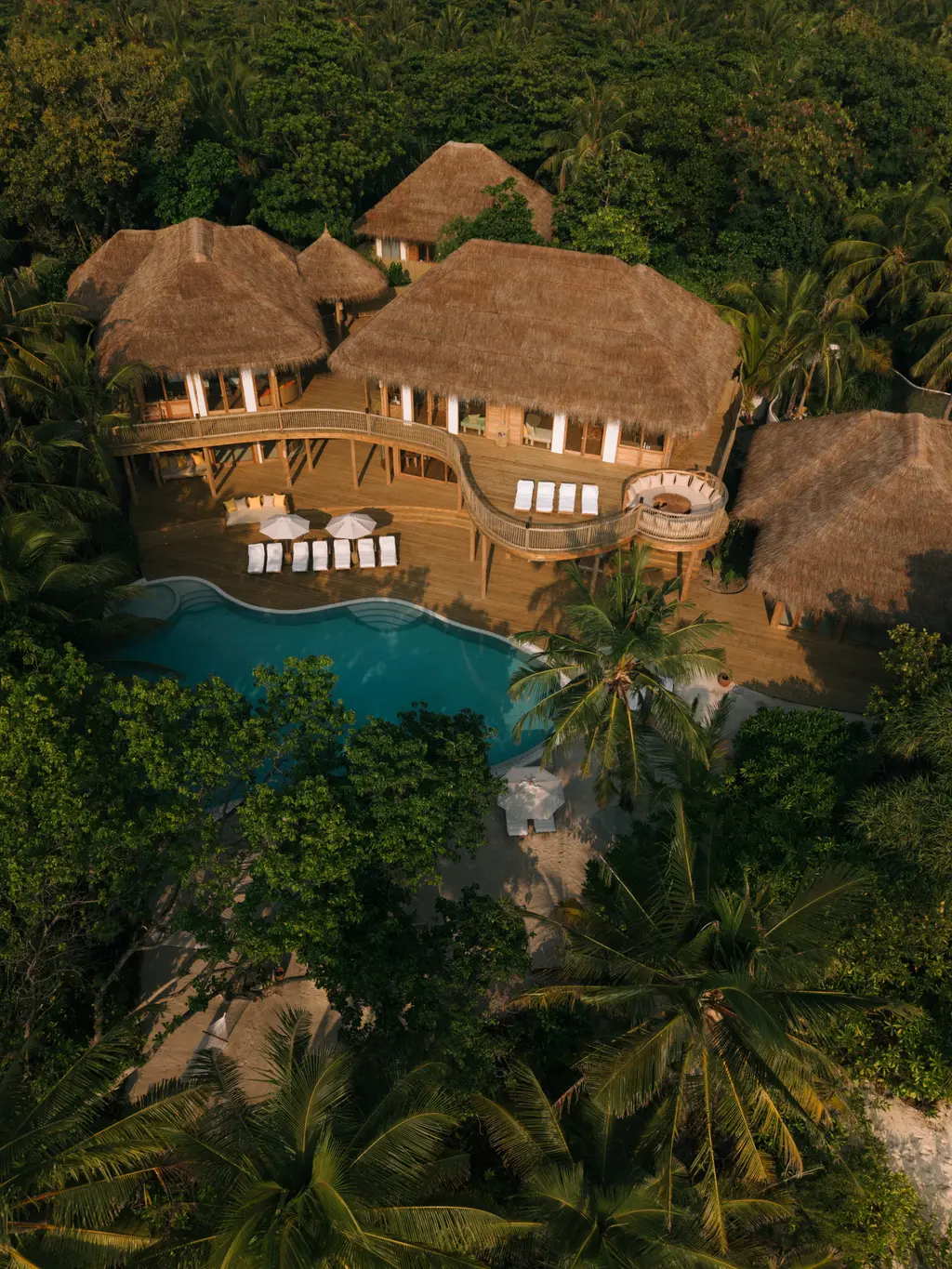 One of the Estates from the air: thatched roofs and a pool in the jungle