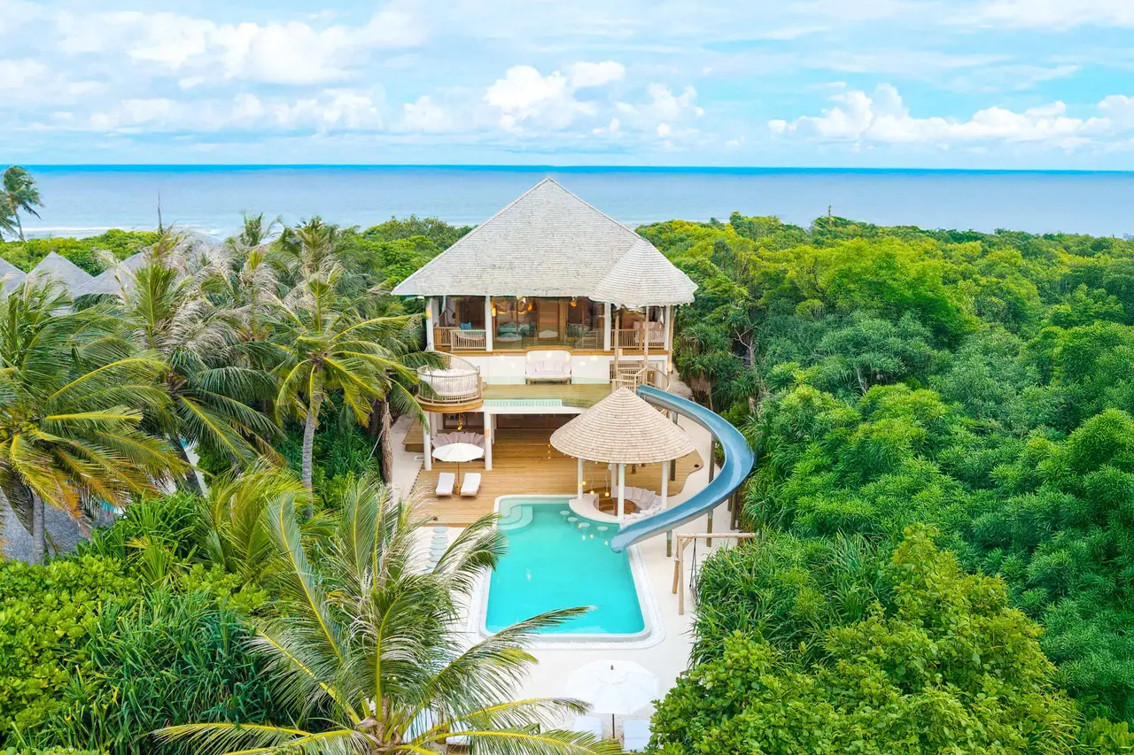 Villa 29 among the palms, the slide curving down to the pool and the sea beyond