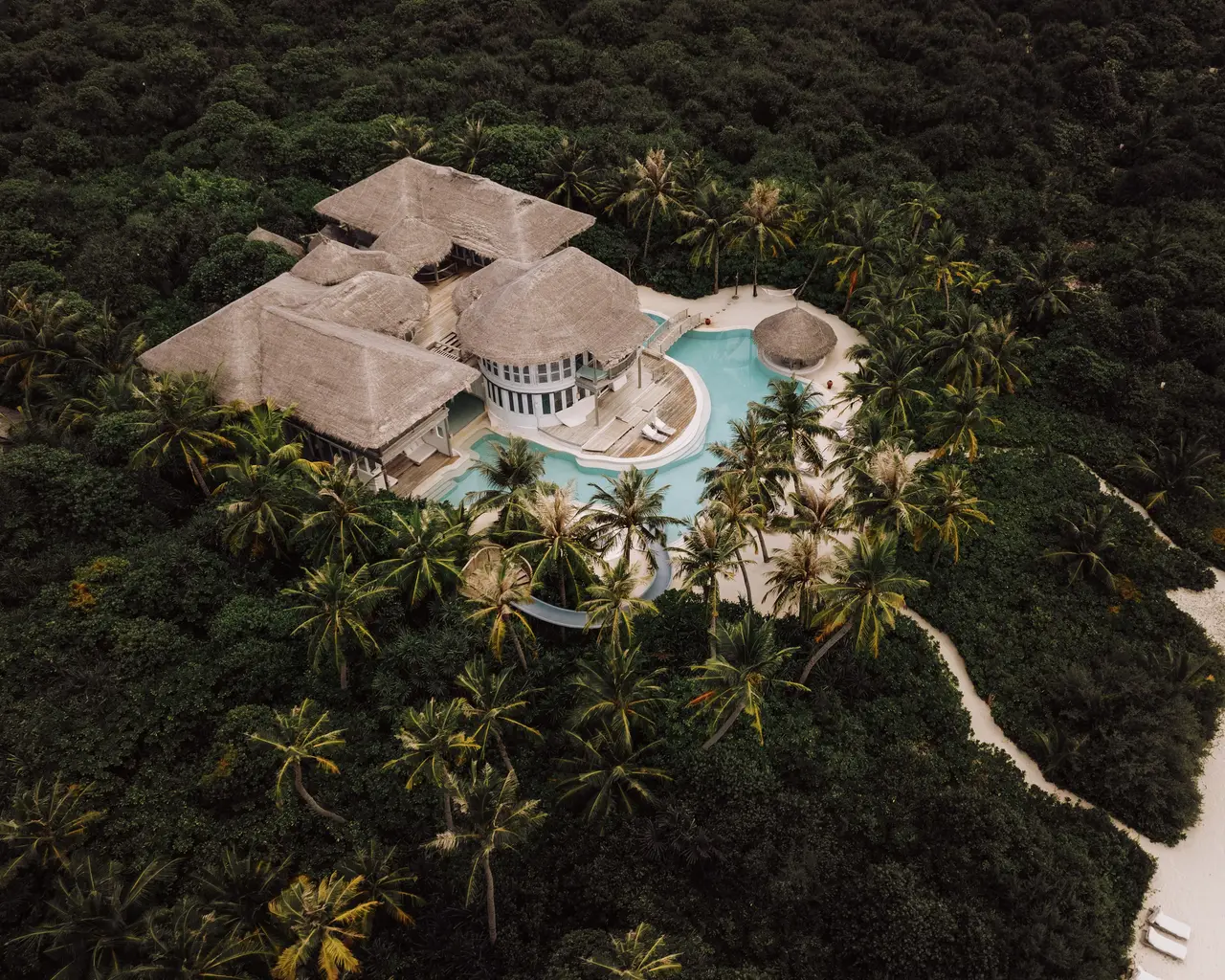 Villa 28 from the air: thatched roofs among the trees and its private pool
