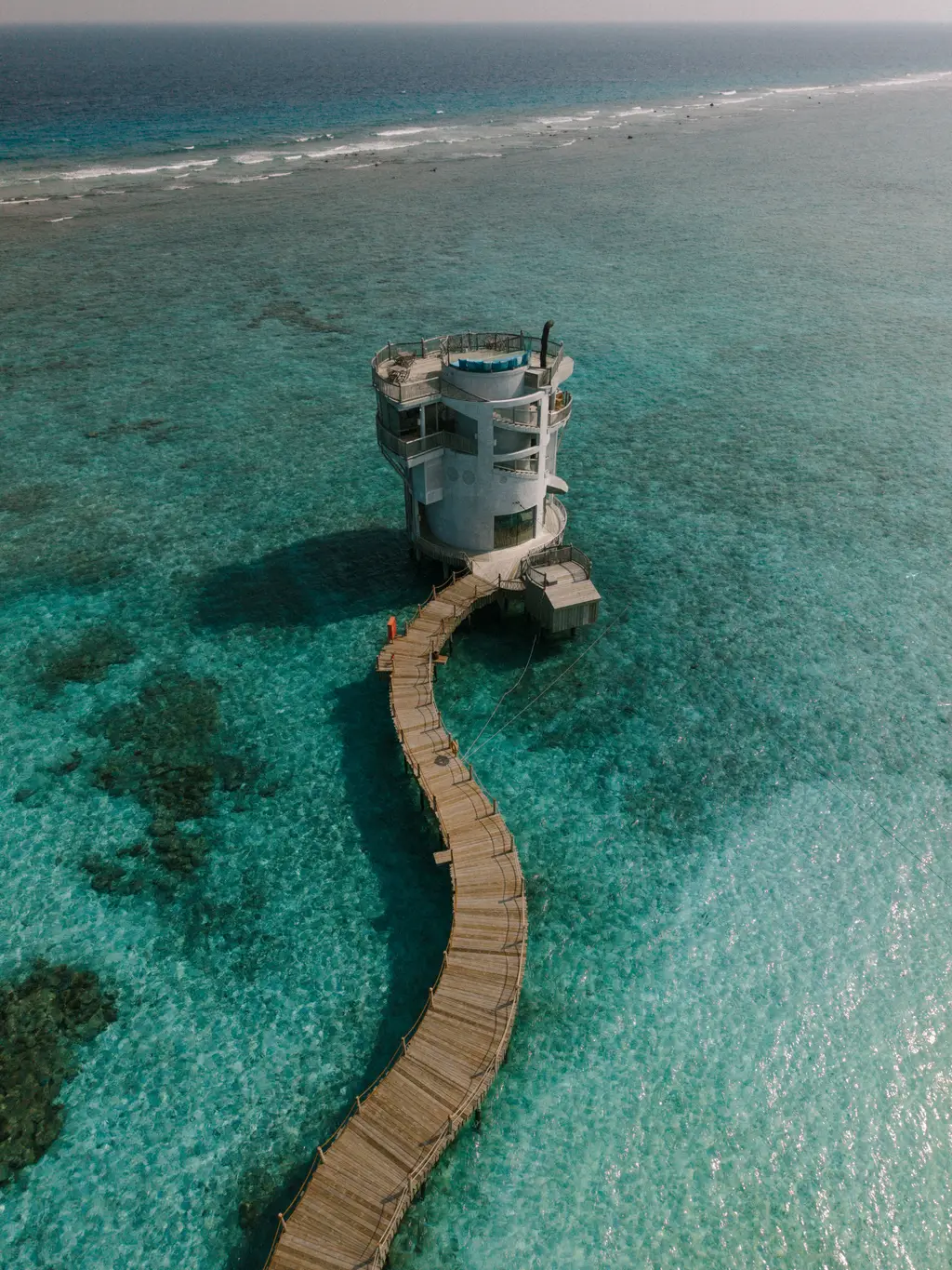 The round tower of Out of This World in the middle of the lagoon, reached by a long timber boardwalk.