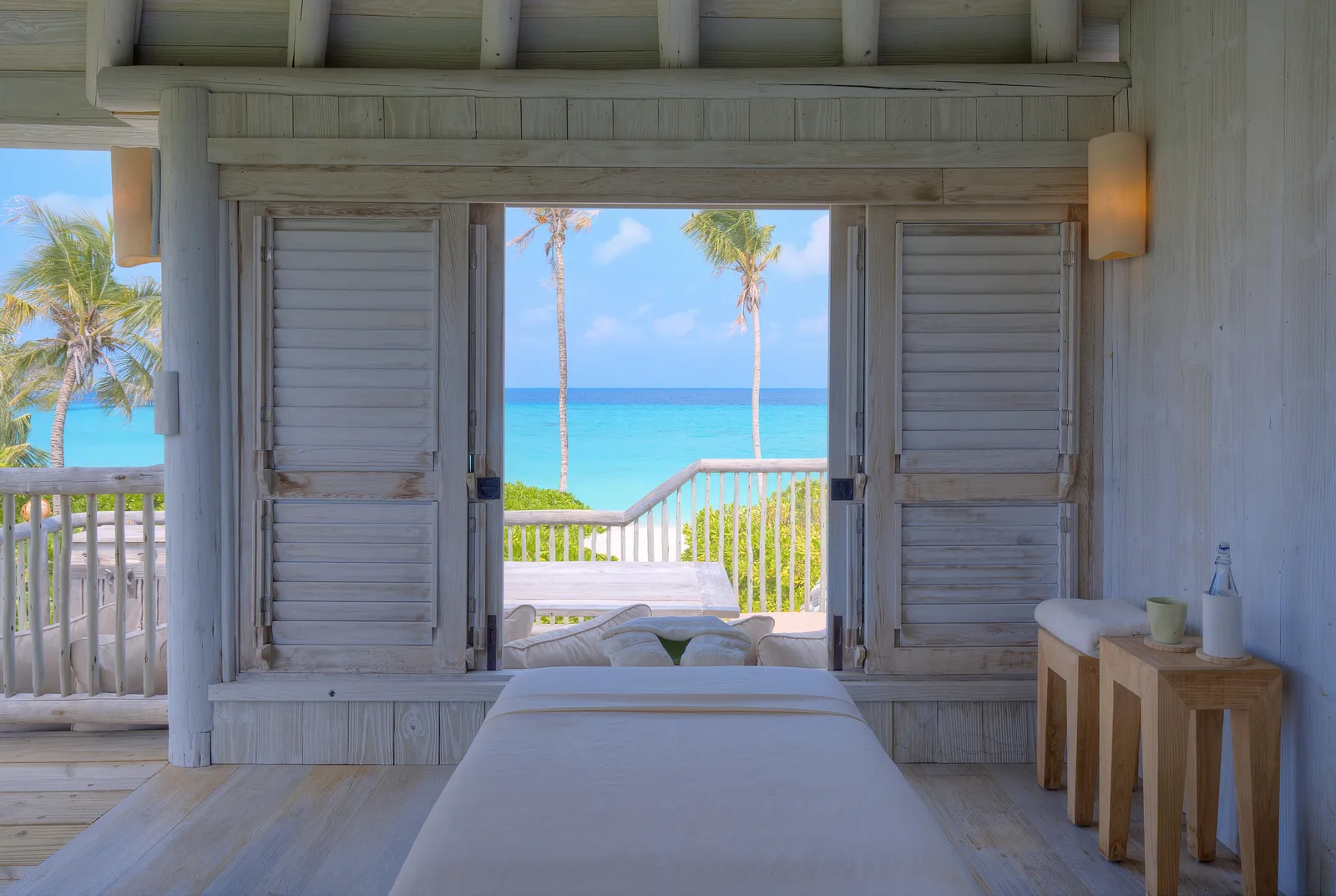 The treatment room upstairs in a Beach Villa, with its massage table and doors open to the palms and the sea.
