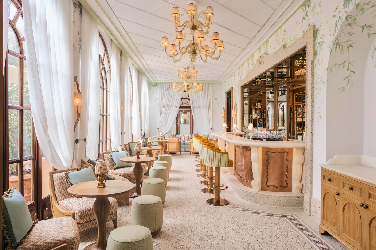 Baratta Sedici bar: a white veranda with chandeliers, the marble counter with striped stools and round tables.