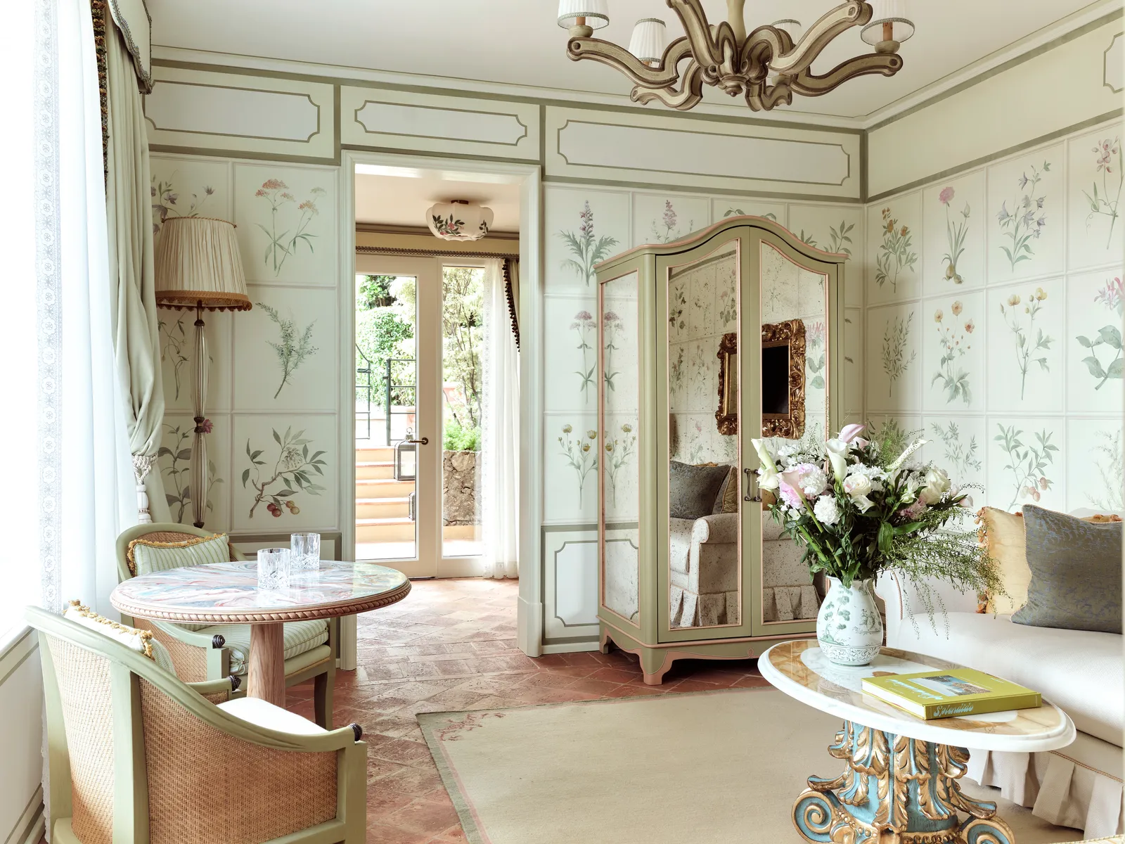 The Flora Suite’s living room, its walls painted with botanical motifs, the round table and the terracotta floor.