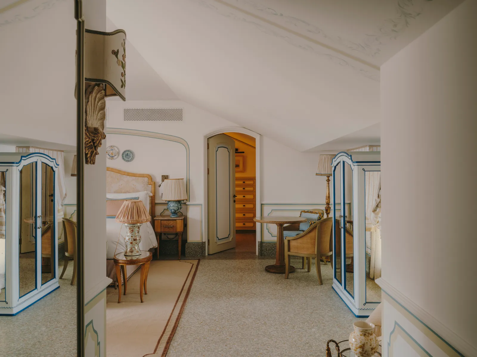 A Glicine Junior Suite under a sloping ceiling, with the bed, the desk and 2 French windows.