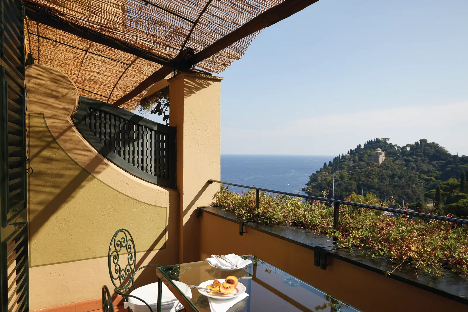 A Glicine Suite’s balcony, breakfast on the iron table and Portofino’s headland over the sea.