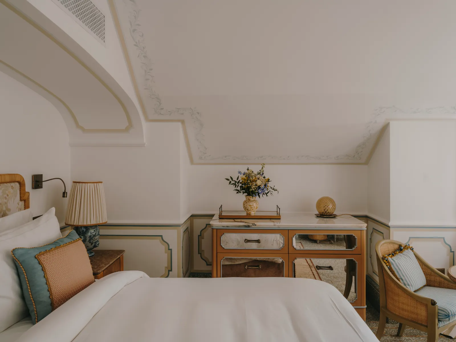 A Splendido Junior Suite: the bed in front, the painted console and a wicker armchair.